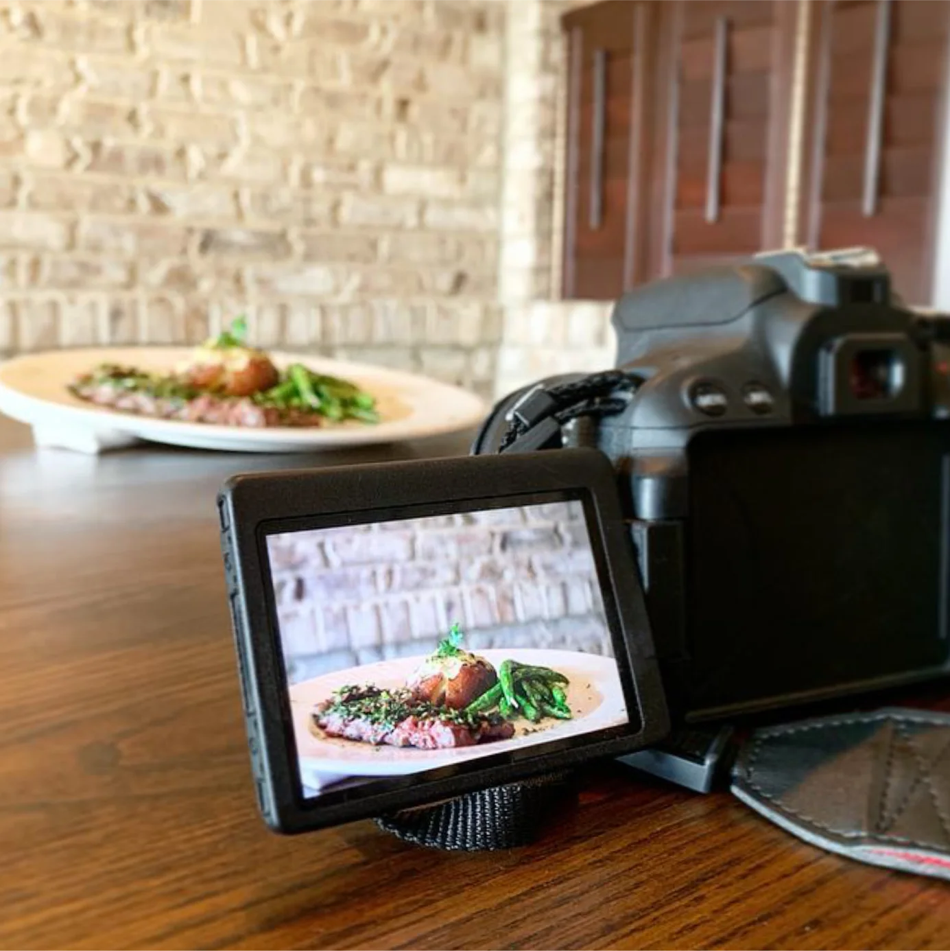 Image of a photoshoot for a restaurant. You can see the dinner plate in the background, and on the display screen of the digital DSLR camera .